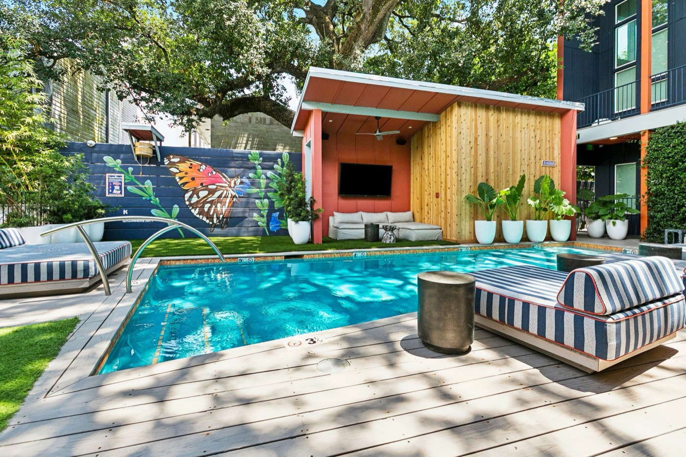 The Syd's pool with striped loungers, butterfly mural, and TV cabana